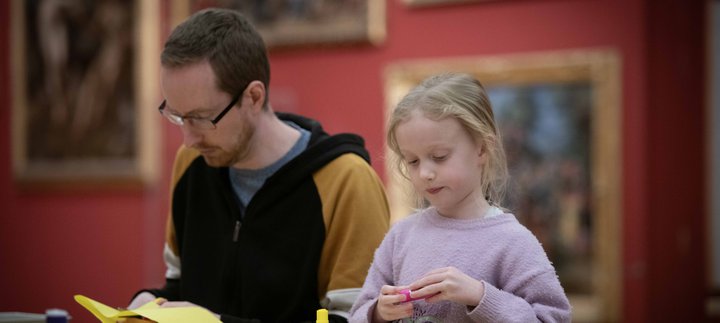 An adult and child sat a table with craft materials.