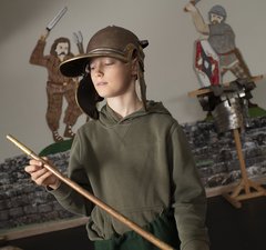 Boy wearing Roman helmet holding spear
