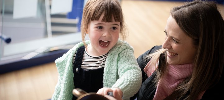 little girl laughs with mum in museum
