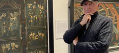 Bob Olley standing in front of his paintings in South Shields Museum
