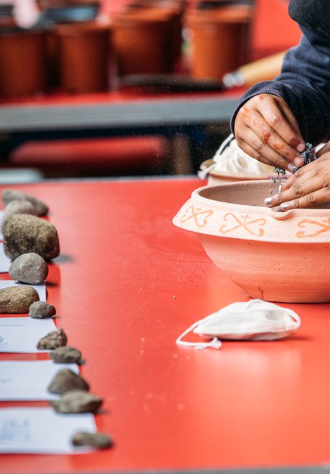 Children's hands planting herbs in a container on a table