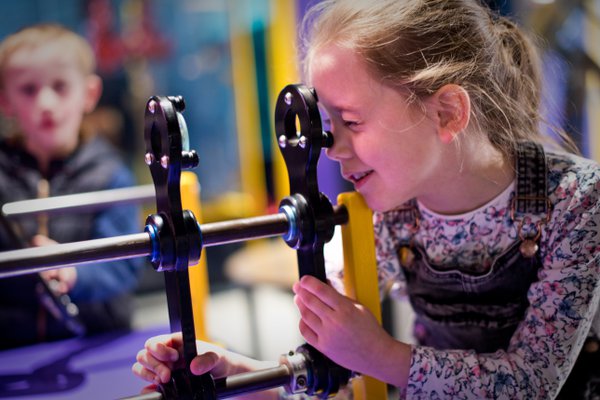 A girl peering through a lens at a museum.