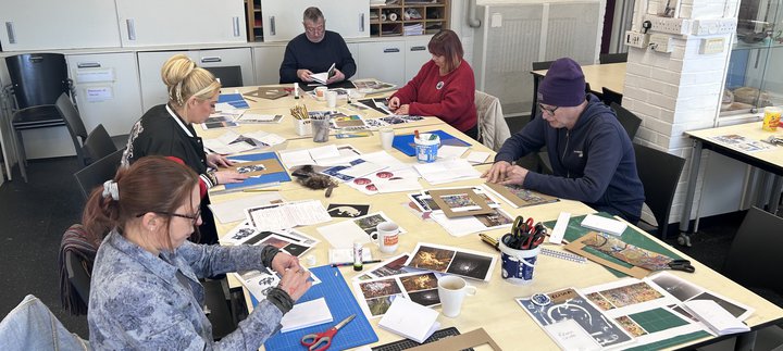 A group of adults sat around a large table, taking part in a craft activity together.