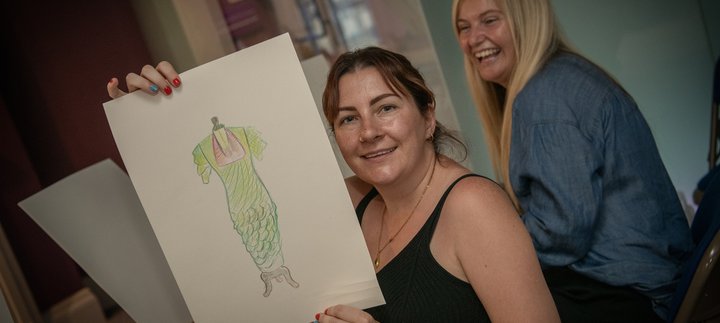a woman holds up her sketch of a vinatge dress