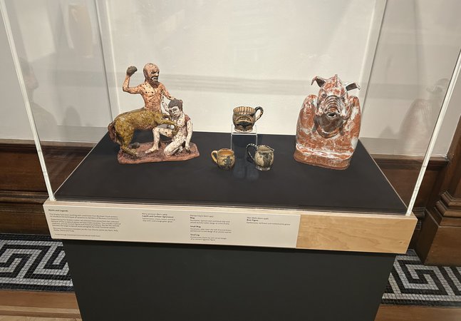 A glass display cases with a selection of ceramic objects. The label for the cases reads 'Myths and Legends' in black text on a cream background.