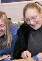 two women smile and talk in the museum