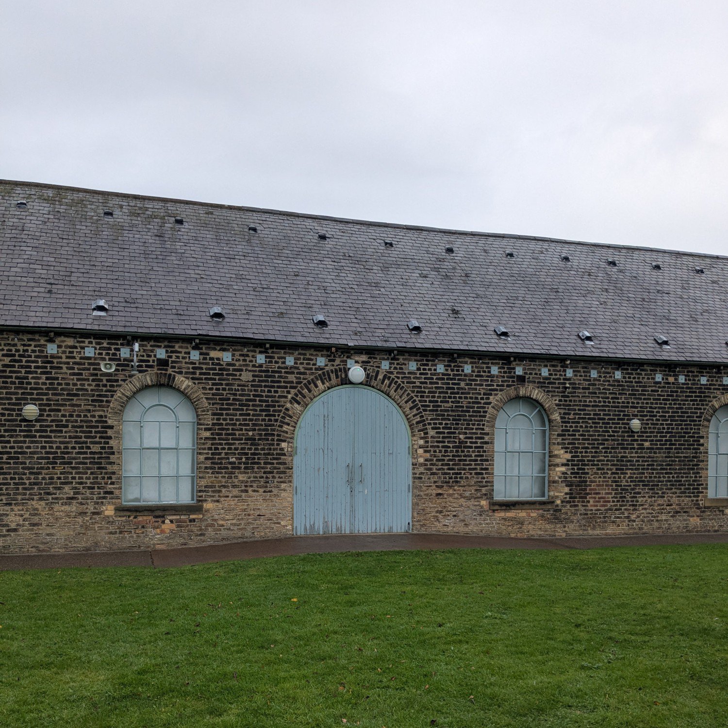 Brick building with arched windows and large gated doors.