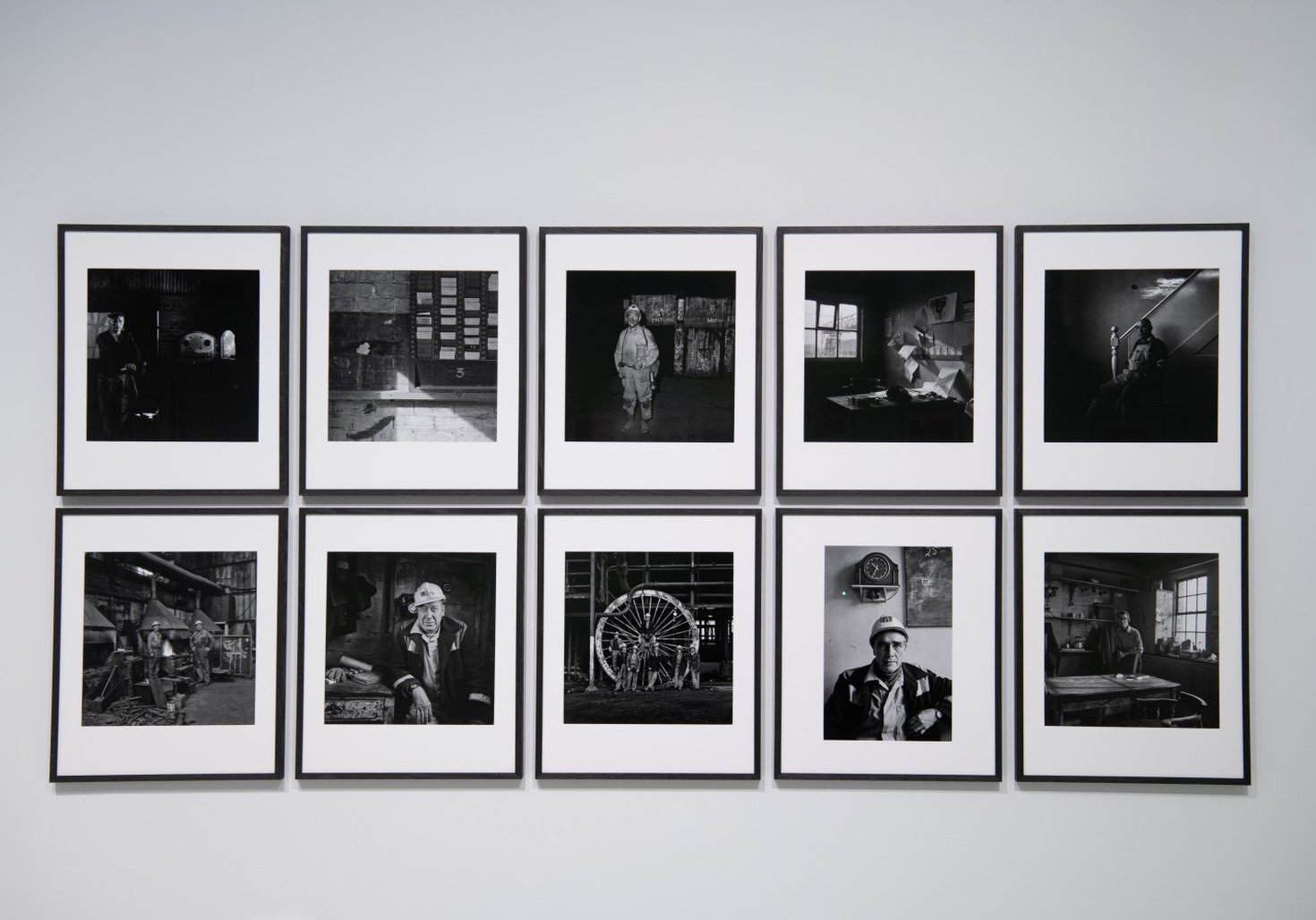 10 framed black and white photographs of coal mining scenes on a wall in a museum