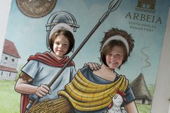 Two young children sticking their faces through cut out of Roman people