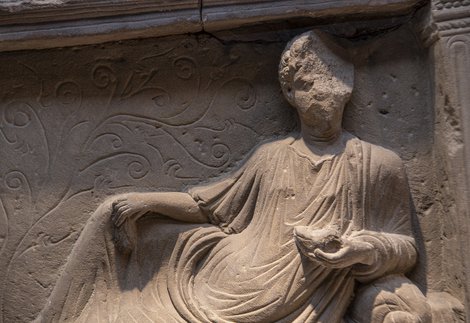 Close up of stone tombstone showing man reclining.
