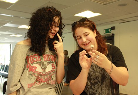 2 young women, one of the left looking at an object the woman on the right is holding (a mounted bird skull model)