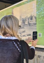 Image of Metro station poste with women looking on in interest with phone