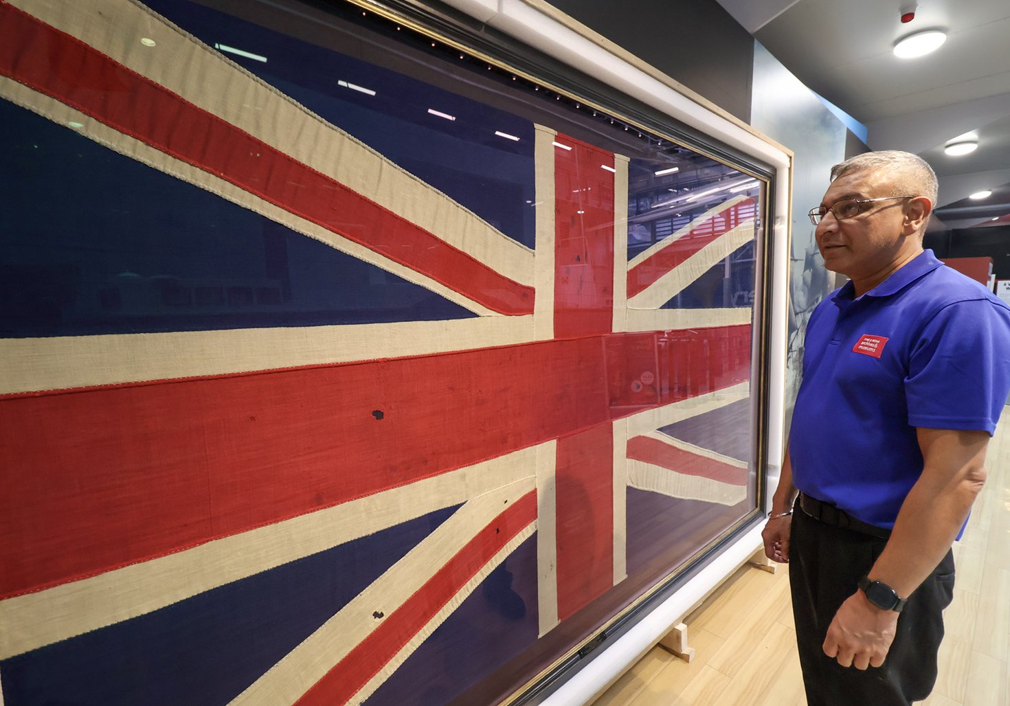 a staff member in blue t-shirt looks at the Trafalgar Flag