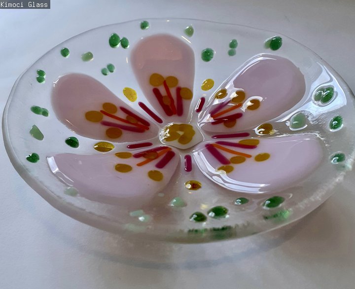 A photograph of a clear glass bowl with a pink flower.