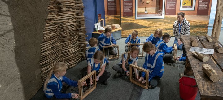 Group of children learning wattle and daub technique