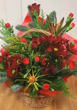 A photograph of a Christmas themed floral arrangement in a wicker basket. 