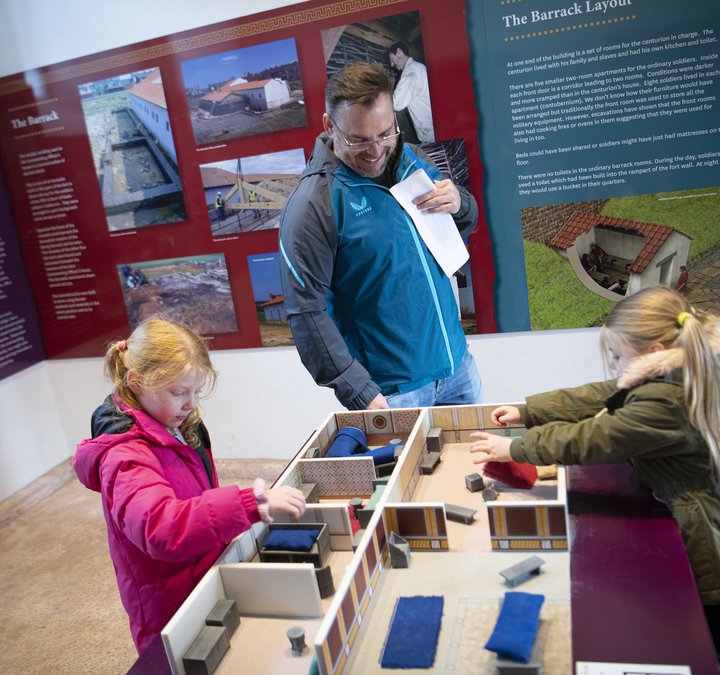 Man with two children looking at model of building