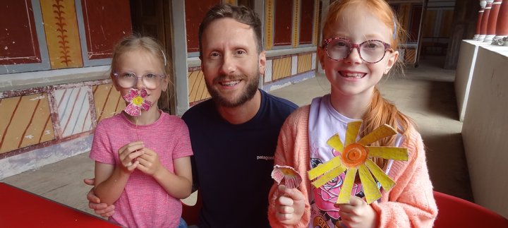 Two young girls with their dad holding the flowers they've made from egg boxes