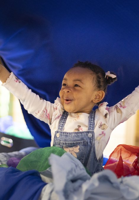 A little girl is smiling with her arms in the air