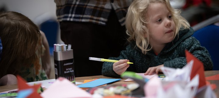 A young child holds a felt-tip.