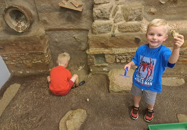 Two boys in Time Quest - 1 is digging and 1 is holding up an object, 