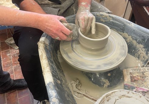 A participant using a pottery wheel to make a bowl