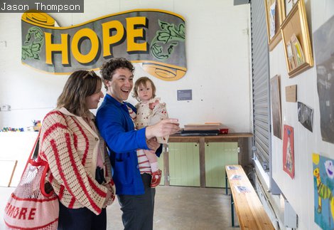 A family smiling and standing and pointing at something on the wall in the creative space at Woodhorn Museum