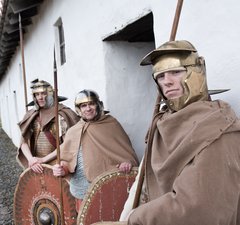 3 Roman soldiers stand outside barrack block 