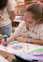 A child sitting and drawing in a large gallery space