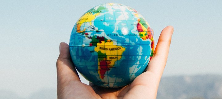a hand holding a ball patterned like the earth
