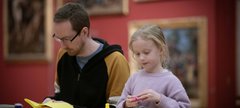 An adult and child sat a table with craft materials.
