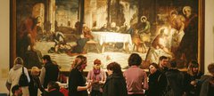 A crowd is gathered around a large painting. 