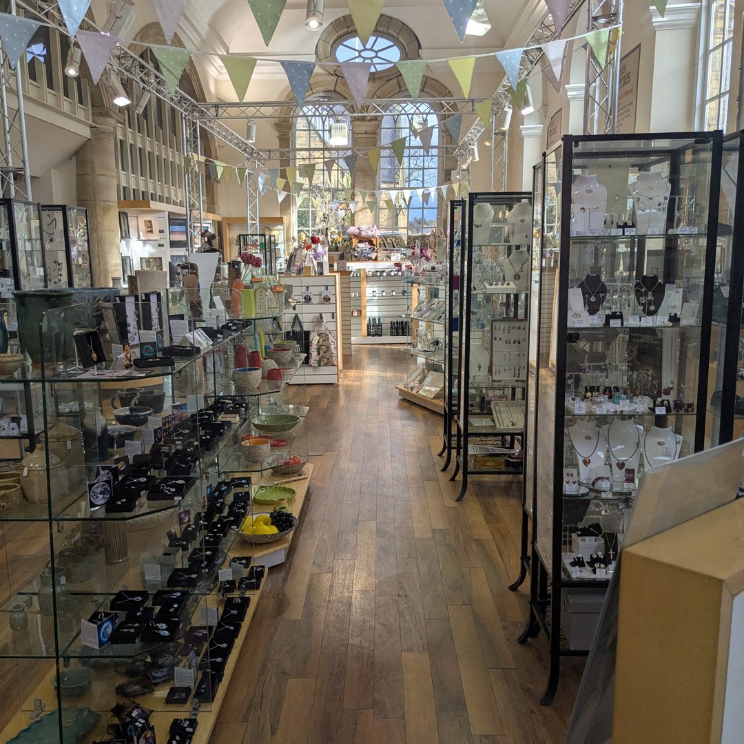 A gift shop. Display cabinets containing products and decorative bunting at ceiling level.