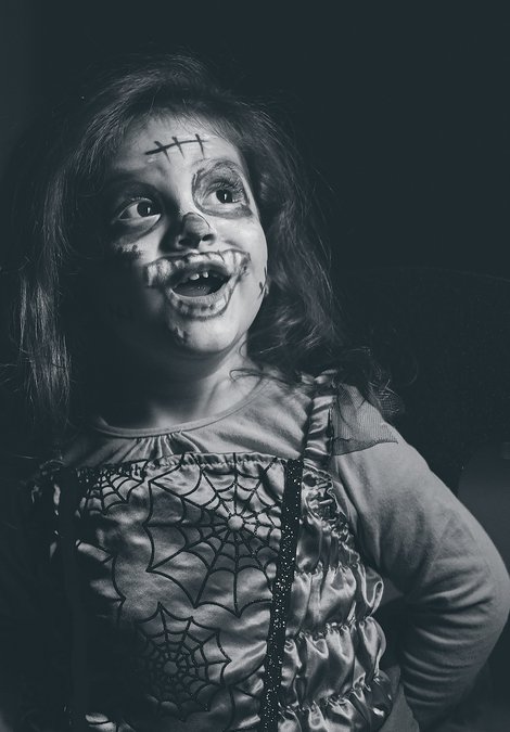 little girl dressed up for Halloween with face paint 