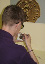 Person using a magnifying glass to look at ancient artefacts