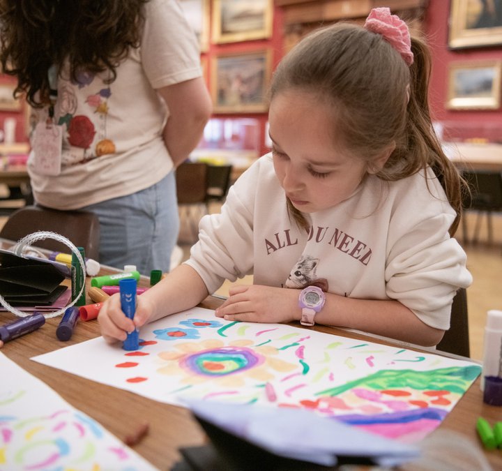 A child sitting and drawing in a large gallery space