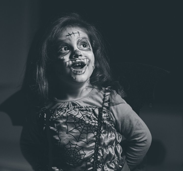 little girl dressed up for Halloween with face paint 