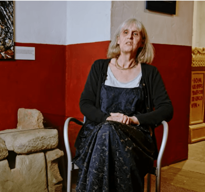 Female curator sat in a gallery next to Roman stone toilets