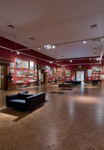 A photograph of the interior of the Shipley Art Gallery. The walls are red and there are many paintings on the walls in gold frames.