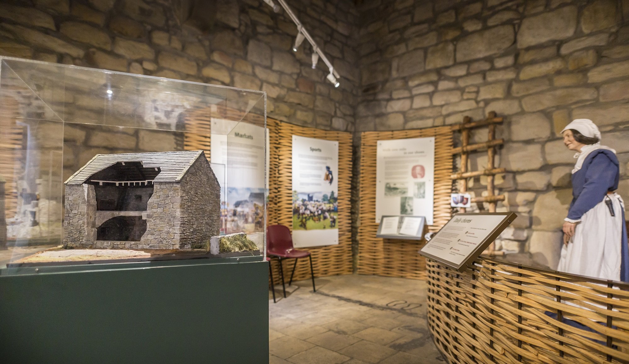 View of a museum gallery with models, interpretation boards and mannequin in Medieval dress.