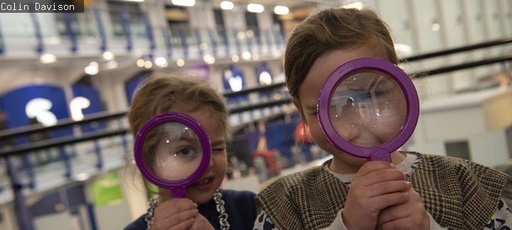 Two girls peer through magnifying glasses