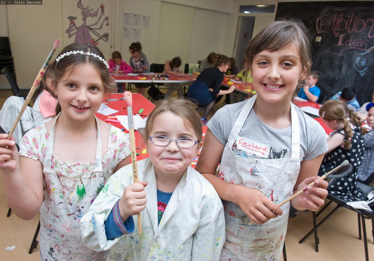 three girls holding paintbrushes