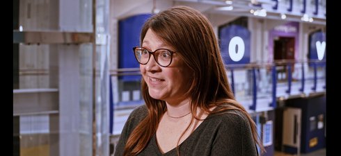 Screenshot of talking women with brown hair in museum