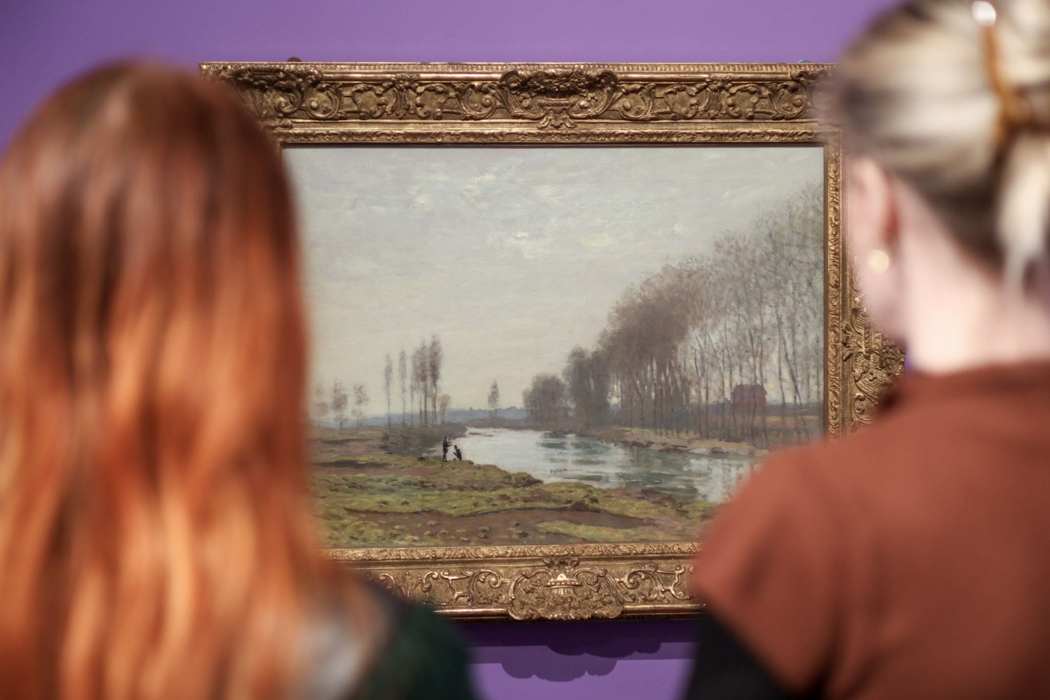 Two women looking at a landscape painting in gilded frame. Two women looking at a landscape painting in gilded frame.