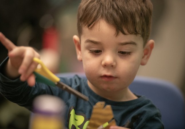 A young child is cutting some paper. 
