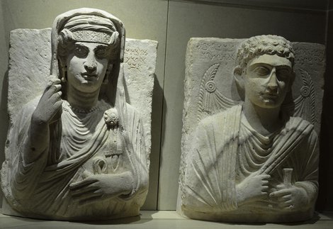 Two finely carved stone artefacts showing human figures. They are both shown wearing draped fabrics