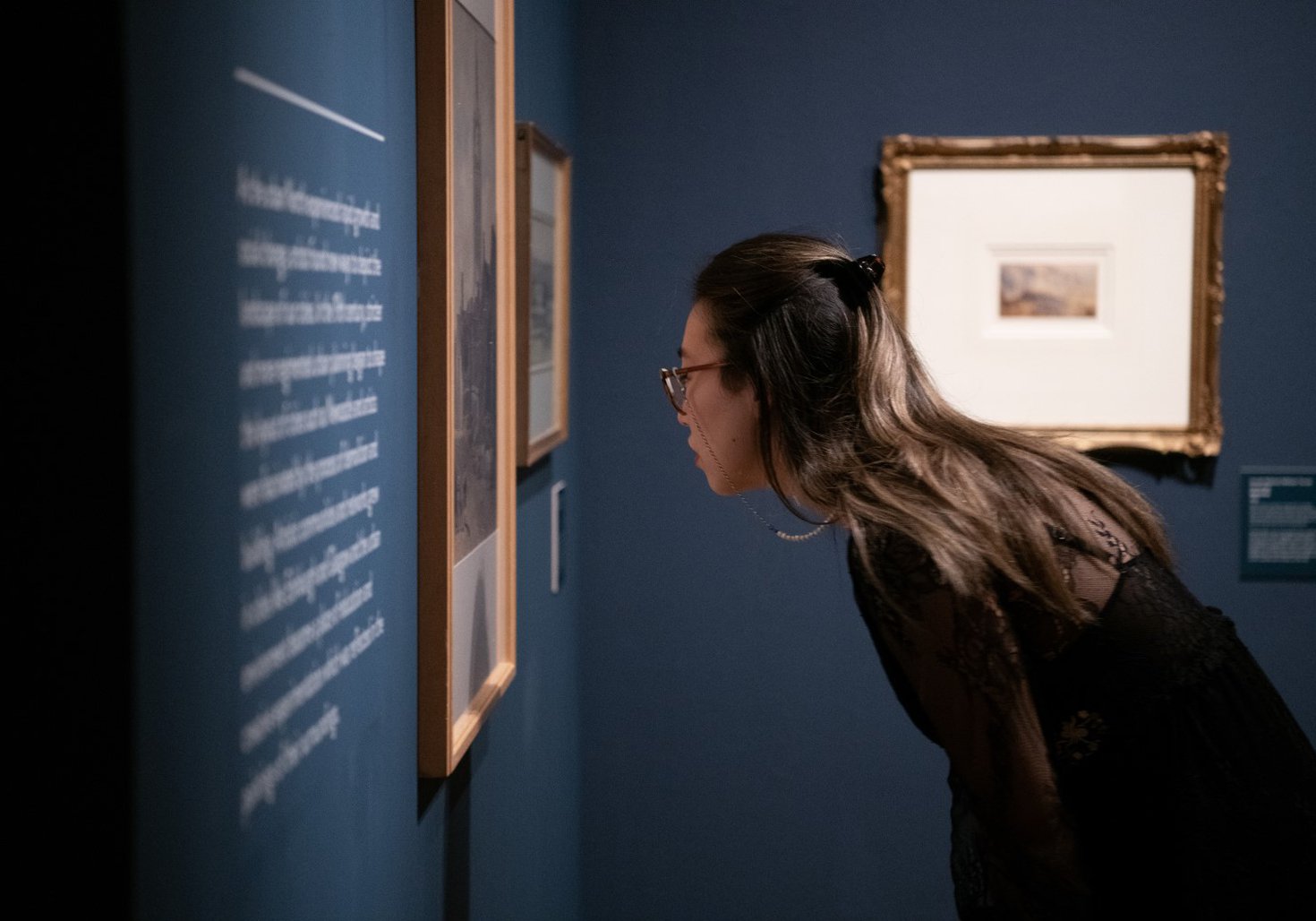 A woman looks closely at a painting