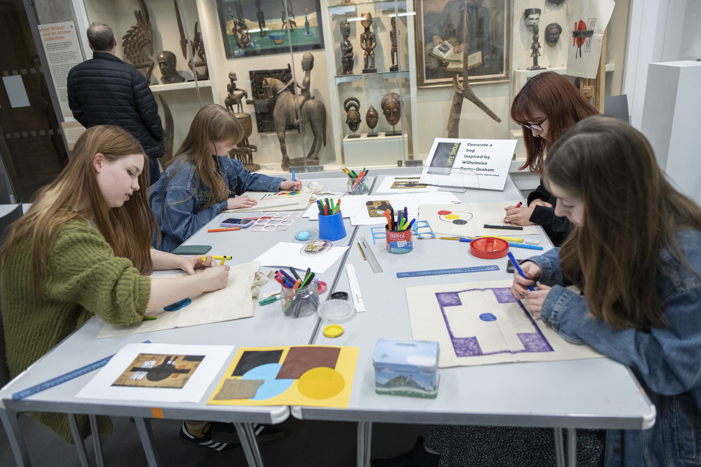 A group of girls sit around a table, drawing A group of girls sit around a table, drawing