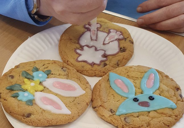 A photograph of someone decorating cookies with a spring theme, including bunnies and flowers.