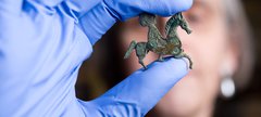 A person is holding a small horse brooch found at Arbeia.